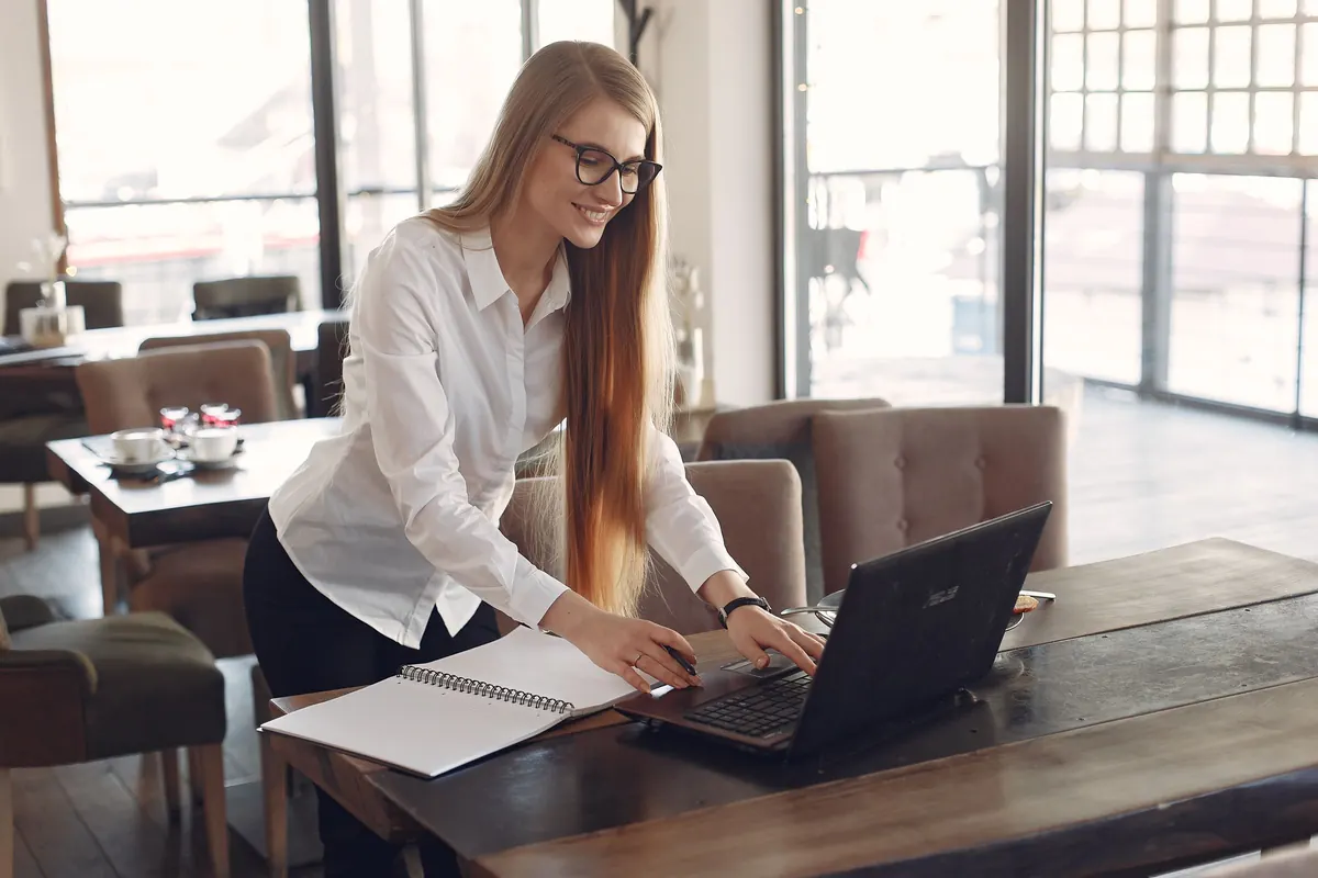 Small business owner working on a laptop at a table in a bright cafe