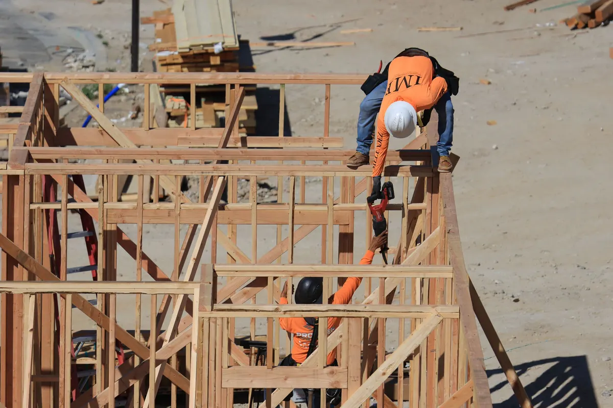 Two construction workers framing a wooden structure on a job site