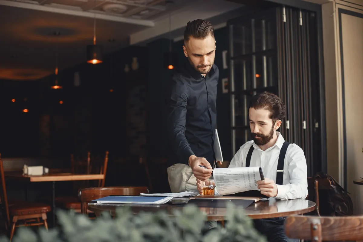 Two businessmen discussing work over menus at a restaurant