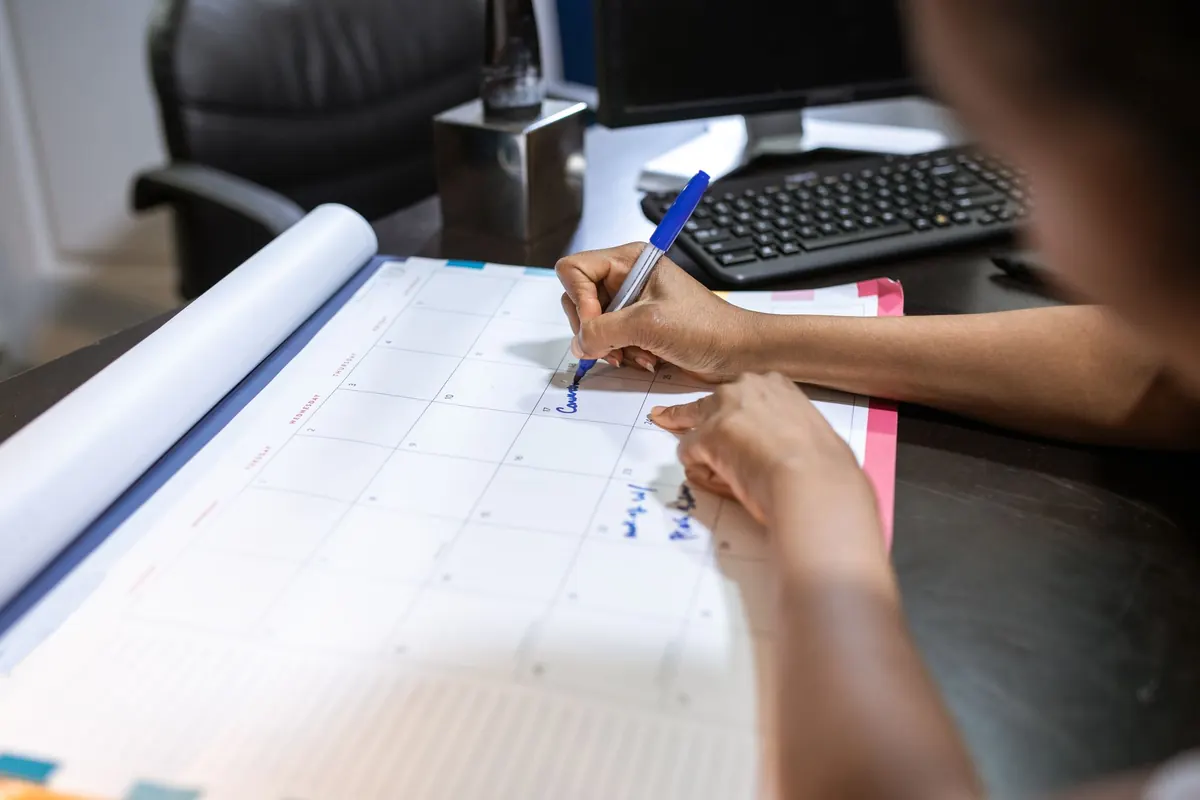 Person writing on a desk calendar