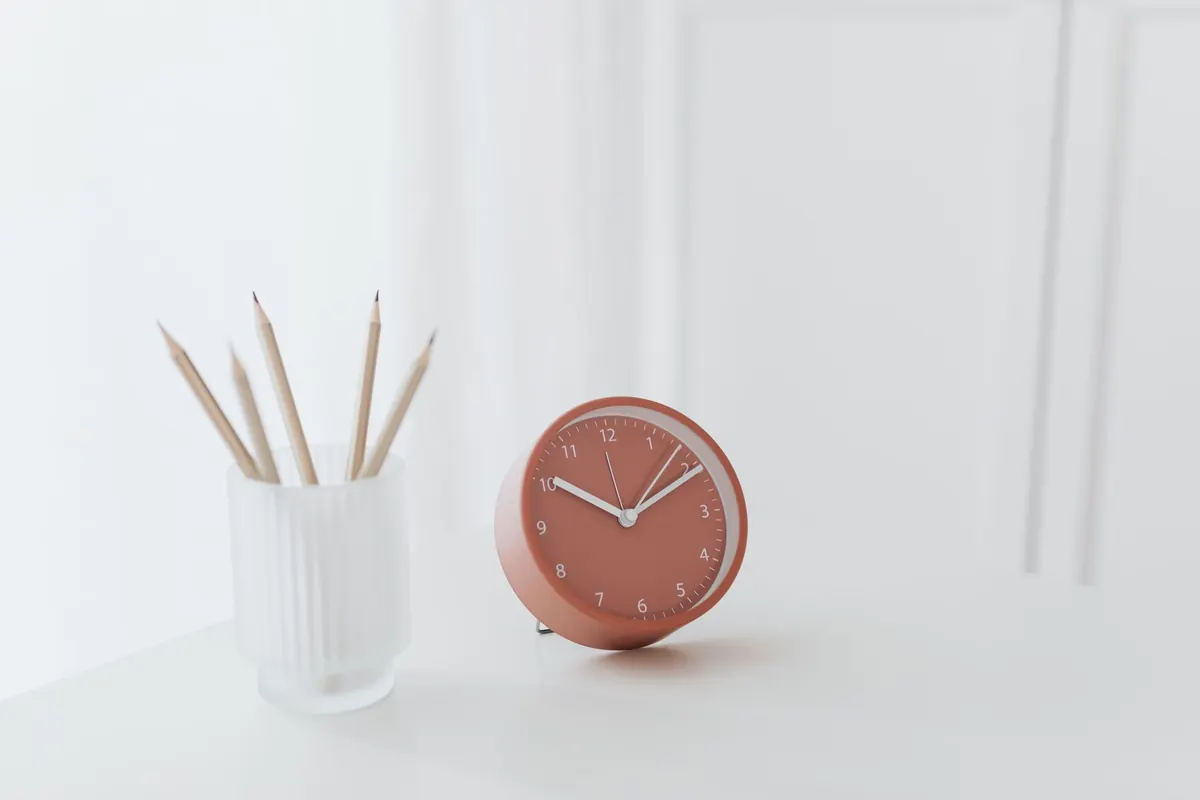 Red clock and pencils on a desk