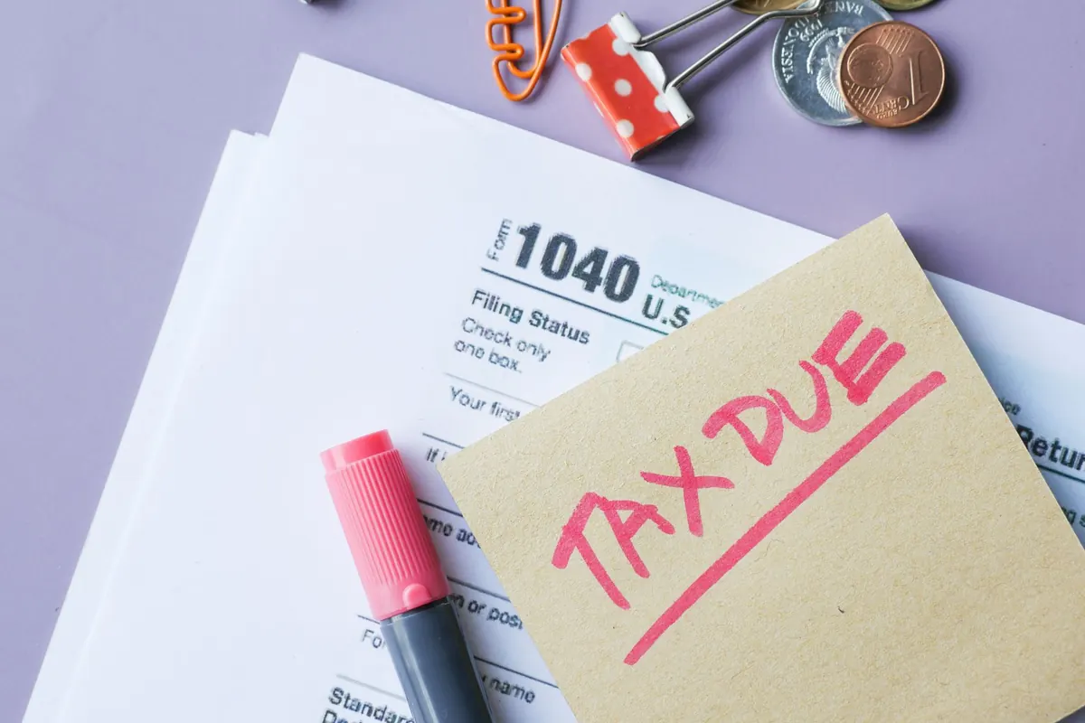 Tax form with a tax due note, pen and paper clips on a desk