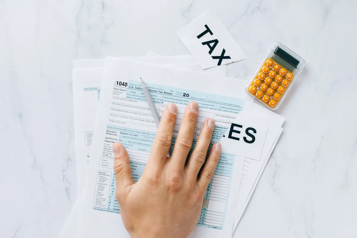 Hand on a federal tax form next to a calculator