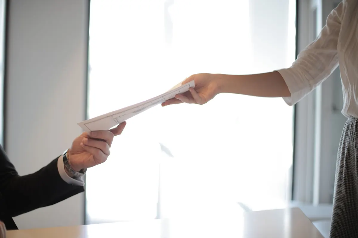 Job applicant handing her documents across a desk