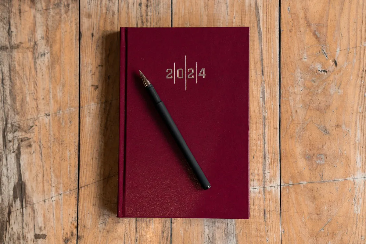 Pen resting on a planner calendar on a desk